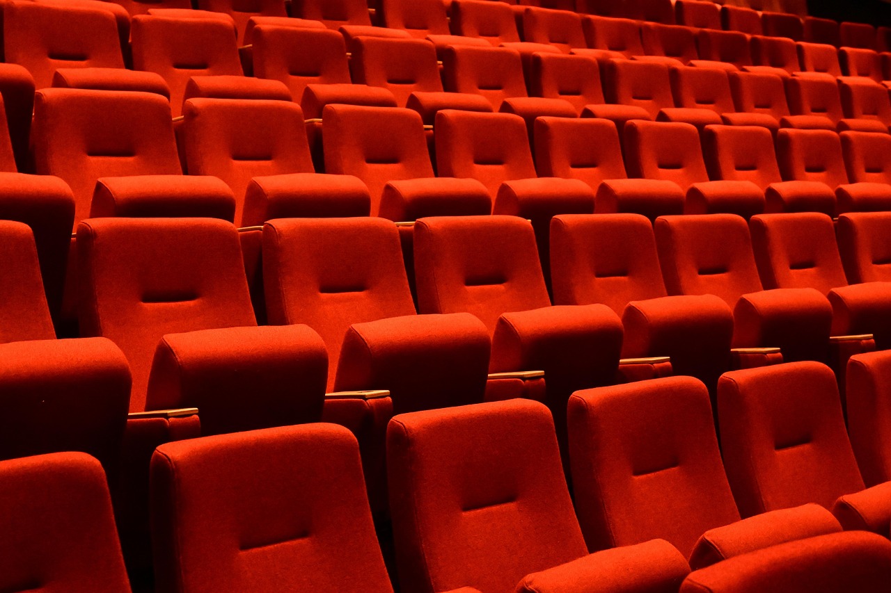 Close view of rows of red cinema seats stacked in tiers, with no audience in the room.
